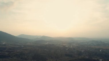 Gün ışığında, yumuşak ışık ve katmanlı tepelerle şafak vakti puslu dağ manzarası