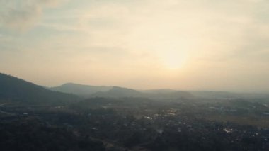 Sakin bir vadide puslu bir gün doğumu tepelerin siluetleri ve gün ışığında yumuşak altın bir gökyüzü