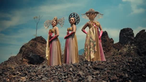Kolme Naista Taiteellisissa Puvuissa Poseeraamassa Dramaattisessa Kivimaisemassa Pilvisessä Taivaassa Päivänvalossa — kuvapankkivideo