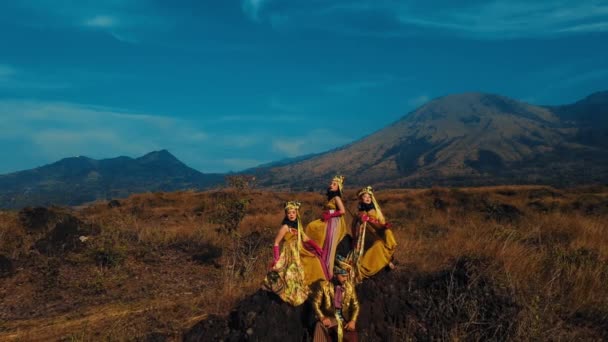 昼間の山の背景で自然の風景でパフォーマンスするカラフルな衣装の伝統的なダンサーのグループ — ストック動画