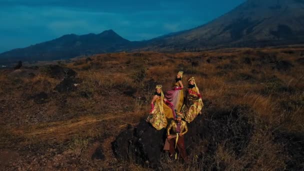 夕暮れの背景にある山々と険しい風景を歩く伝統的なドレスの3人の女性 — ストック動画