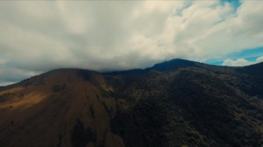 Tepelerin üzerinde bulutlar uçuşan görkemli dağ manzarası. Gündüz vakti arka plan ve doğa temaları için uygundur.