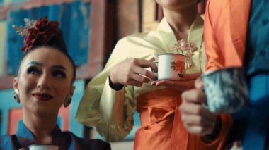 Geleneksel Asya çay seremonisi. Kültürel giyinmiş kadınların gündüz vakti elinde porselen bardak tuttukları bir tören.