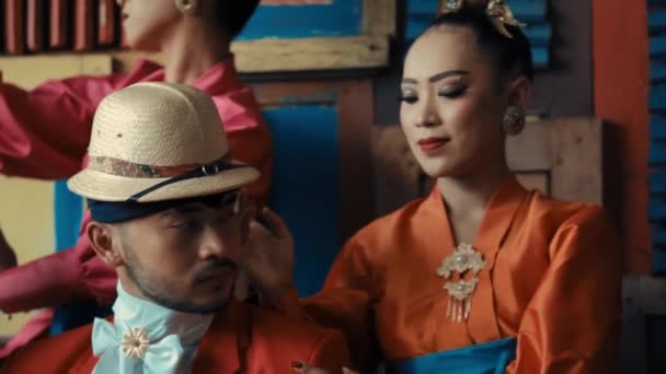 日中のヴィンテージセッティングでエレガントなジェスチャーでポーズするカラフルな服装の伝統的なアジアのカップル — ストック動画