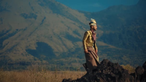 黄昏时分 身穿帝王服装的传统战士站在岩石上 背景是雄伟的高山 — 图库视频影像
