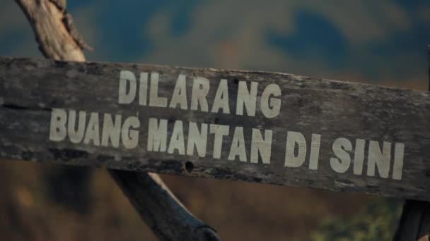 日光浴时 带有印尼文的乡村木制标志 背景模糊不清 — 图库视频影像