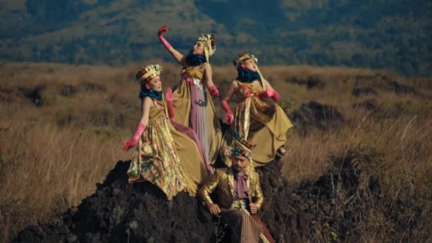 バックグラウンドの山を持つ険しいフィールドで劇的にポーズする精巧な中世の衣装の3人の女性 — ストック動画
