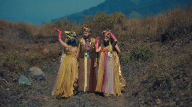 Renkli kostümlü geleneksel dansçılar gündüz vakti doğal bir ortamda gösteri yapıyorlar.