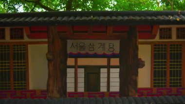 Her ikisi de turist olan genç bir adam ve kadın geleneksel bir Kore restoranının önünden geçiyorlar. Hangul tabelasında 