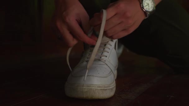 朝の間に白いスニーカーに靴紐を結ぶ手のクローズアップ — ストック動画