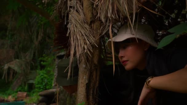 戴着帽子的人从热带树叶后面的丛林里探出头来 — 图库视频影像