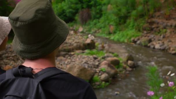 Человек Зеленой Шляпе Смотрит Спокойный Ручей Окружении Пышной Зелени Дневное — стоковое видео