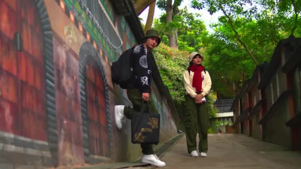 Parkta Grafiti Duvarının Yanından Geçen Iki Genç Yetişkin Sabah Saatlerinde — Stok video
