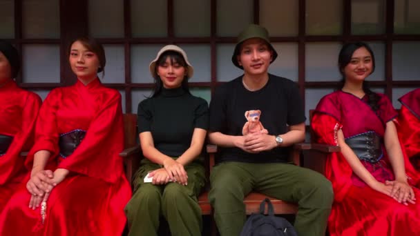 Grupa Młodych Dorosłych Tradycyjnym Czerwonym Stroju Siedzi Razem Uśmiechniętym Mężczyzną — Wideo stockowe