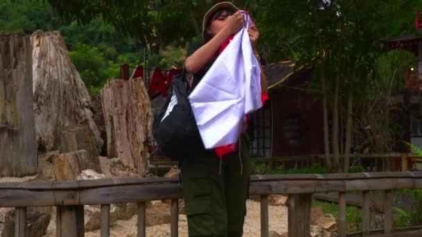 Tourist Mit Hut Und Rucksack Steht Morgens Auf Einer Holzbrücke — Stockvideo