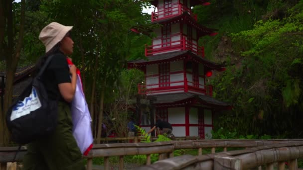 Людина Традиційному Вбранні Йде Мосту Червоною Пагодою Задньому Плані Серед — стокове відео