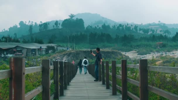Человек Стоящий Деревянном Мосту Живописным Видом Пышные Зеленые Холмы Пасмурное — стоковое видео