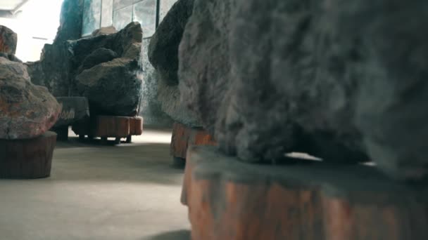 光天化日下画廊内木制基座上有大石头的现代艺术装置的抽象视图 — 图库视频影像