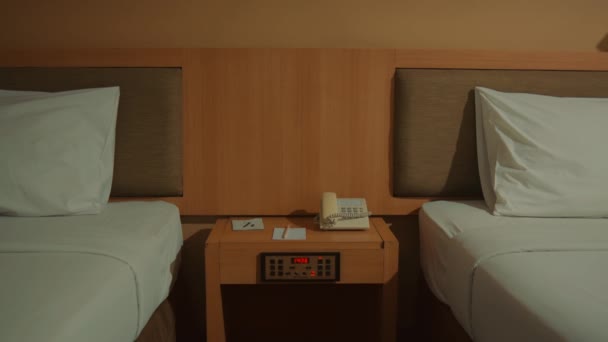 舒适的宾馆房间 有两张单人床 洁白的床上用品 床头柜 还有电话和闹钟 夜间采暖照明 — 图库视频影像
