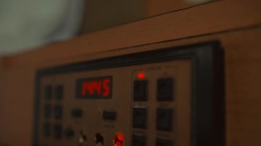 Saat 14: 44 'ü gösteren bir otel odasındaki yatağın başucundaki elektronik kontrol panelini kapat ve parlayan kırmızı bir 