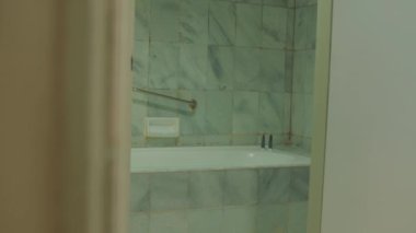 İçi yeşil fayanslarla dolu bir banyo manzarası. Otelin içinde küvet ve tuvalet malzemelerini gösteriyor.