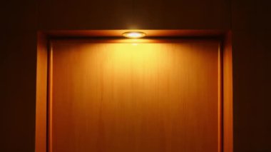 Aydınlatılmış bir duvar lambasının minimalist görüntüsü dokulu bir duvara sıcak bir parıltı saçıyor ve gece boyunca sakin bir ortam yaratıyor.
