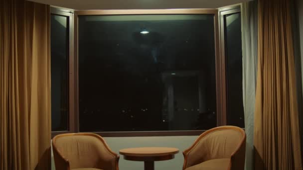 晚上在灯光昏暗的房间里 有两张椅子和一张桌子 有很大的窗户和窗帘 — 图库视频影像