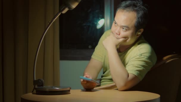 Gestresster Mann Sitzt Mit Handy Einem Tisch Unter Lampenlicht Und — Stockvideo