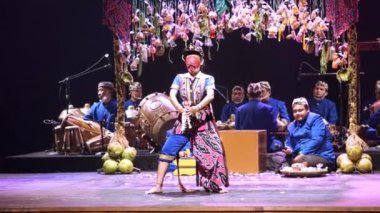 Müzisyenlerle geleneksel halk gösterisi ve sahnede bir dansçı, renkli kostümler ve kültürel dekorasyonlar..