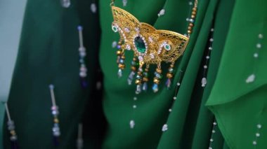 Karmaşık altın mücevher ve yeşil nakışları geleneksel bir Cava kostümünde gösteren yakın plan video..