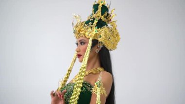 Özenle hazırlanmış altın kaplama bir taç ve yasemin çiçekleri takmış beyaz bir arka plana zarif bir şekilde bakan Cava 'lı bir kadının güzel yan görüntüsü..