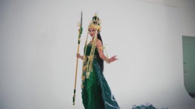 Geleneksel Tayland kostümü giymiş, başlıklı ve mızraklı bir kadın, sabahları kültürel dans yapıyor.