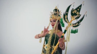 Süslü kostümlü geleneksel Balili dansçı sabahları beyaz bir arka planda hayranla gösteri yapıyor.