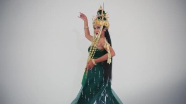 Dekoratif kostümlü geleneksel dansçı gündüz vakti hafif arka planda anlamlı el hareketleriyle kültürel dans yapıyor.