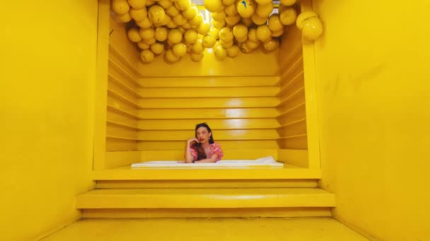 穿着粉色衬衫的女人在黄色房间里用智能手机 白天有楼梯 还有挂着柠檬 — 图库视频影像