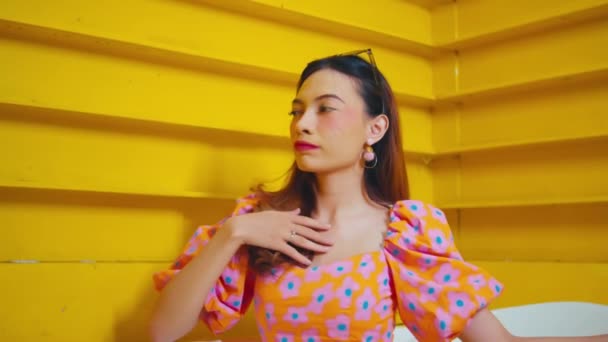 Mulher Elegante Vestido Floral Posando Contra Uma Escada Amarela Vibrante — Vídeo de Stock