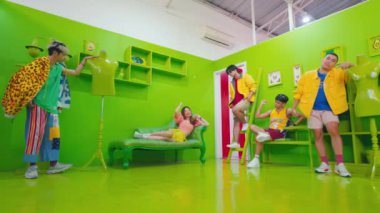 Modayı takip eden bir grup genç, renkli mobilyalar ve sabahları neşeli pozlarla dolu yeşil bir odada eğleniyor.