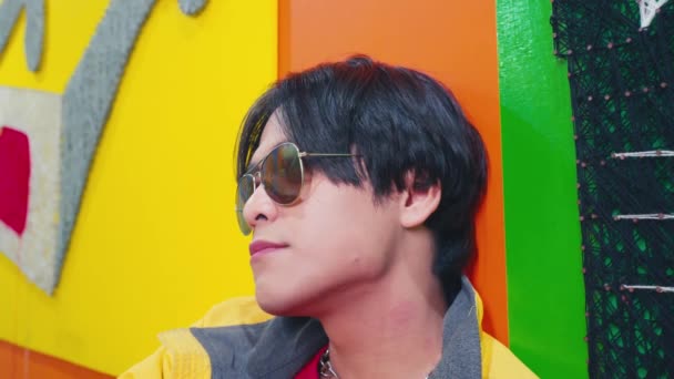 Hombre Con Gafas Sol Relaja Una Caja Colores Brillantes Una — Vídeos de Stock
