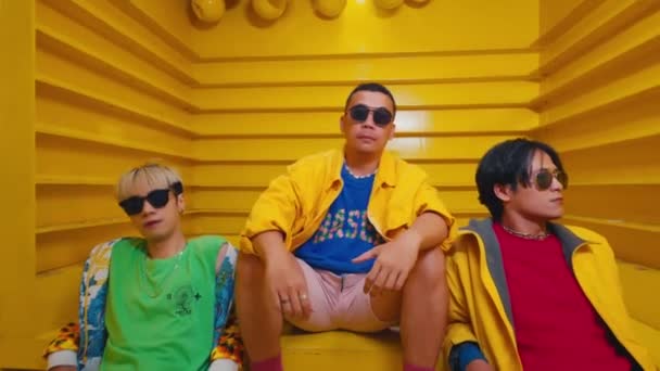 Three Stylish People Wearing Sunglasses Sitting Yellow Stairs Exuding Cool — Stock Video