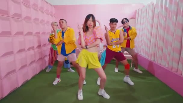 一群时髦的年轻人在一个五颜六色 风格华丽的房间里跳舞 白天的背景是粉色的 — 图库视频影像