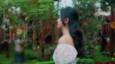 Canlı bitkilerle dolu yemyeşil bir bahçenin keyfini çıkaran bir kadın ve sabahları ağaçlardan sarkan düş kapanları.