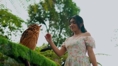 Gülümseyen kadın, sabah yeşilliklerle çevrili bir tavuğu nazikçe okşuyor.