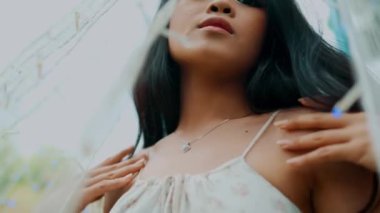 Düşünceli bir ifadeyle genç bir kadının portresi, bulanık dalların arasından bakan, gün ışığında karamsar bir gökyüzü arkaplanı olan