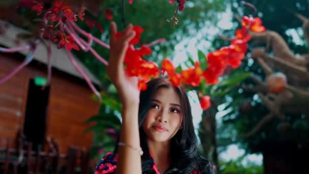 Mujer Serena Tocando Vibrantes Flores Rojas Con Fondo Enfoque Suave — Vídeo de stock