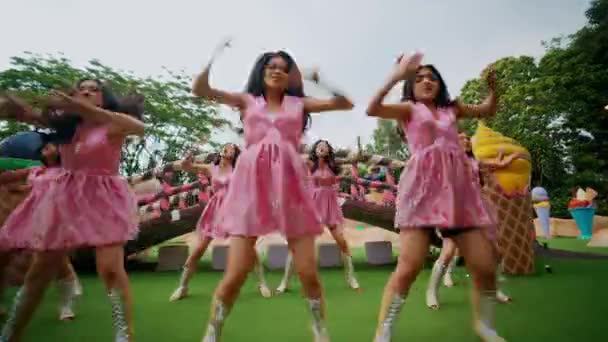 屋外でパフォーマンスするピンクのドレスのダンサーのグループの輝かしい動き 昼間のエネルギーと動きを伝える — ストック動画
