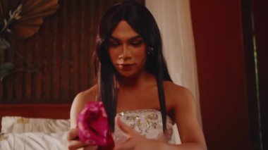 Beyaz elbiseli bir kadının kırmızı geleneksel Endonezya kravat boyası kumaşına (Jumputan) odaklanmış bir ifadeyle baktığı yakın plan..