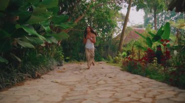 Ağlayan, kahverengi saçlı, doğanın tadını çıkaran yeşil tropik bitki ve ağaçlarla çevrili genç bir kadının yan görüntüsü.