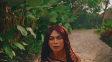 Huzurlu, kızıl saçlı bir kadın... sakin bir bahçe yolunun tadını çıkarıyor. Sabah yemyeşil çimlerle çevrili.