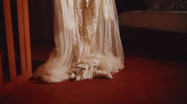 Kırmızı zeminde duran beyaz dantelli gelinliğin altını kapat. Kumaş havuzları zarif, karmaşık dantelleri ve boncukları vurguluyor..