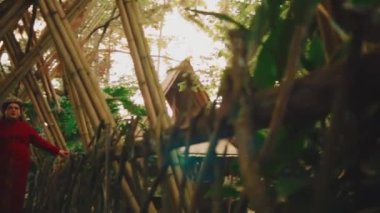Karmaşık bambu yapısına ve yemyeşil tropikal yapraklara odaklanarak geleneksel düğün yerinin sakin atmosferini oluşturan sanatsal çekim..